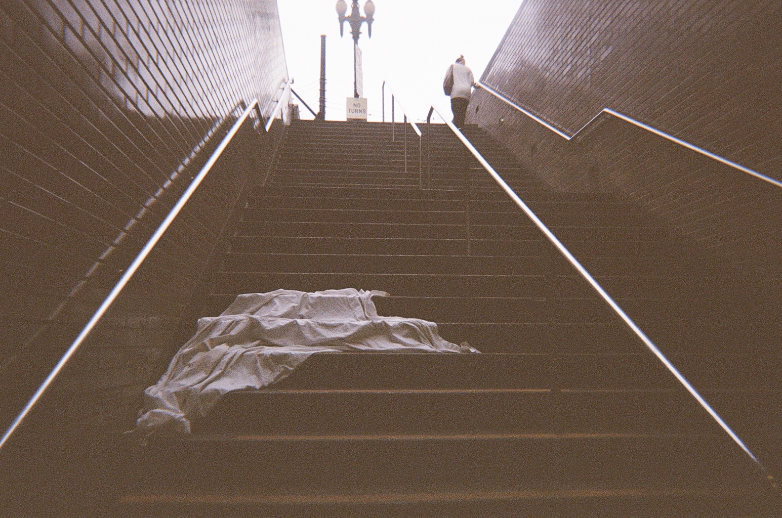 Stairway rising out of a BART station, a blanket abandoned on the steps