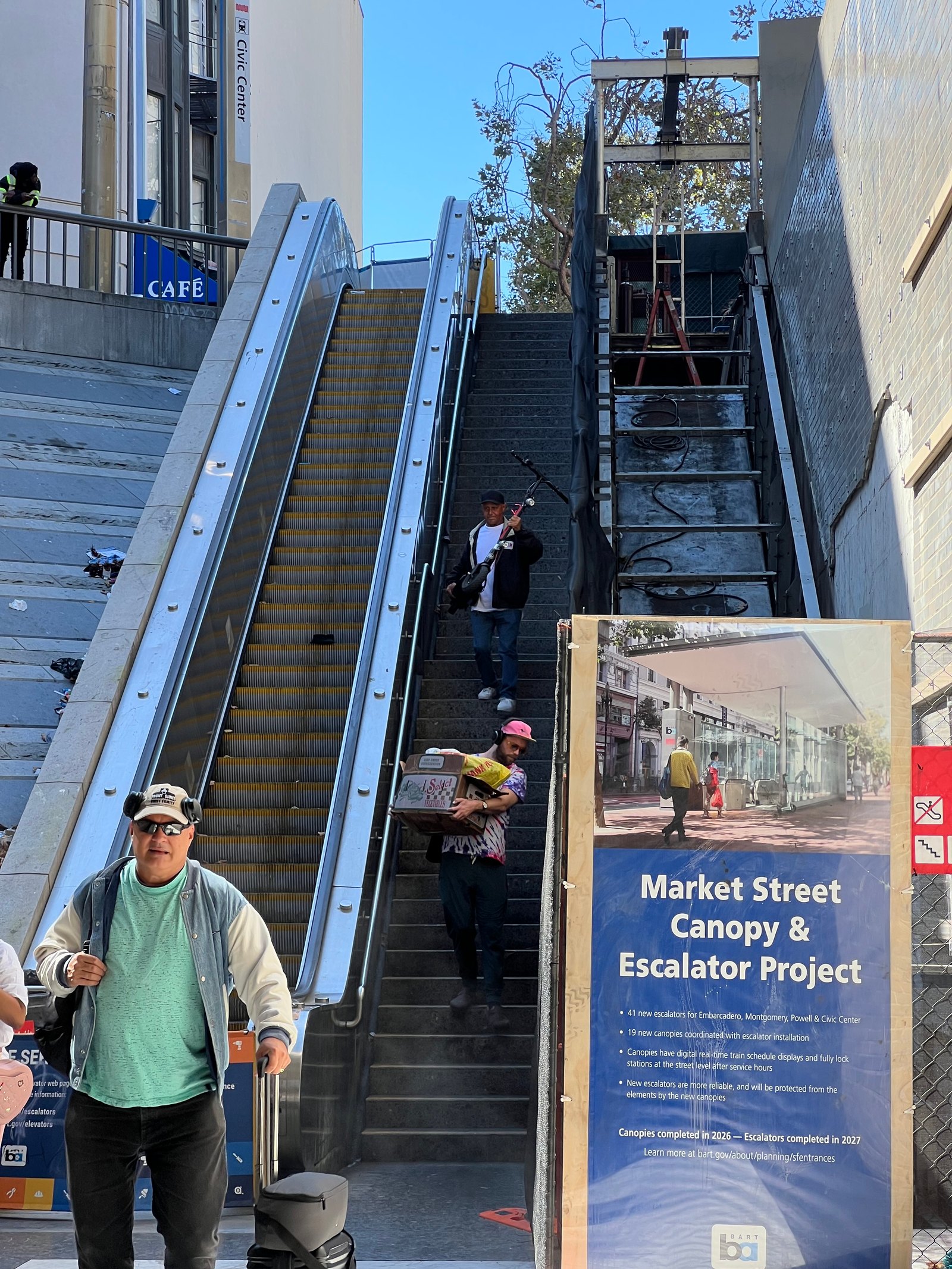 Civic Center entrance — escalator closed for construction under a Market Street Canopy and Escalator Project notice, riders carrying their things down the stairs